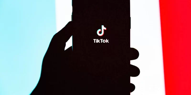 Foto de uma mão segurando um smartphone com o logotipo do TikTok no centro, sendo utilizada para representar a notícia de que o TikTok pode ser banido dos EUA (Estados Unidos)